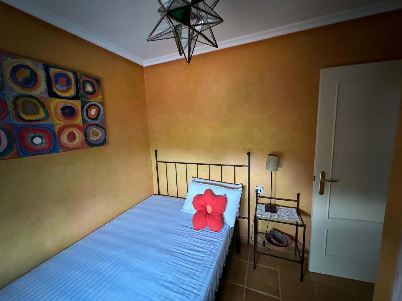 Dormitorio con paredes de estuco naranja, cama individual y lámpara de estrella