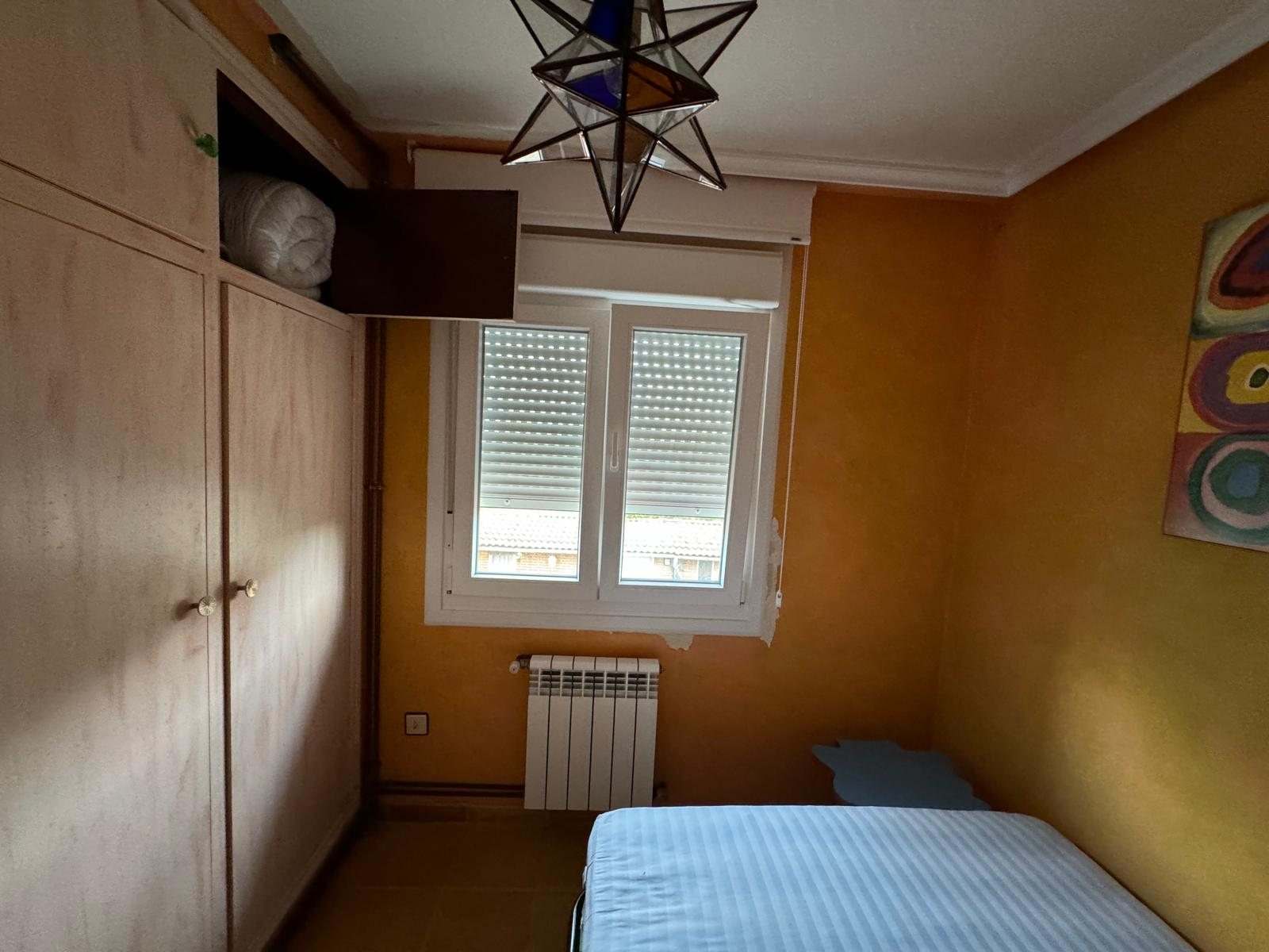 Dormitorio naranja con armario de madera y ventana