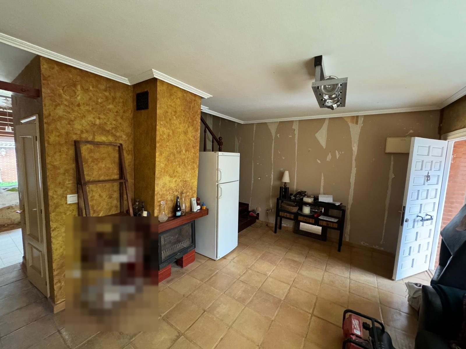 Salón con parte de las paredes ya sin papel y la chimenea todavía en su sitio