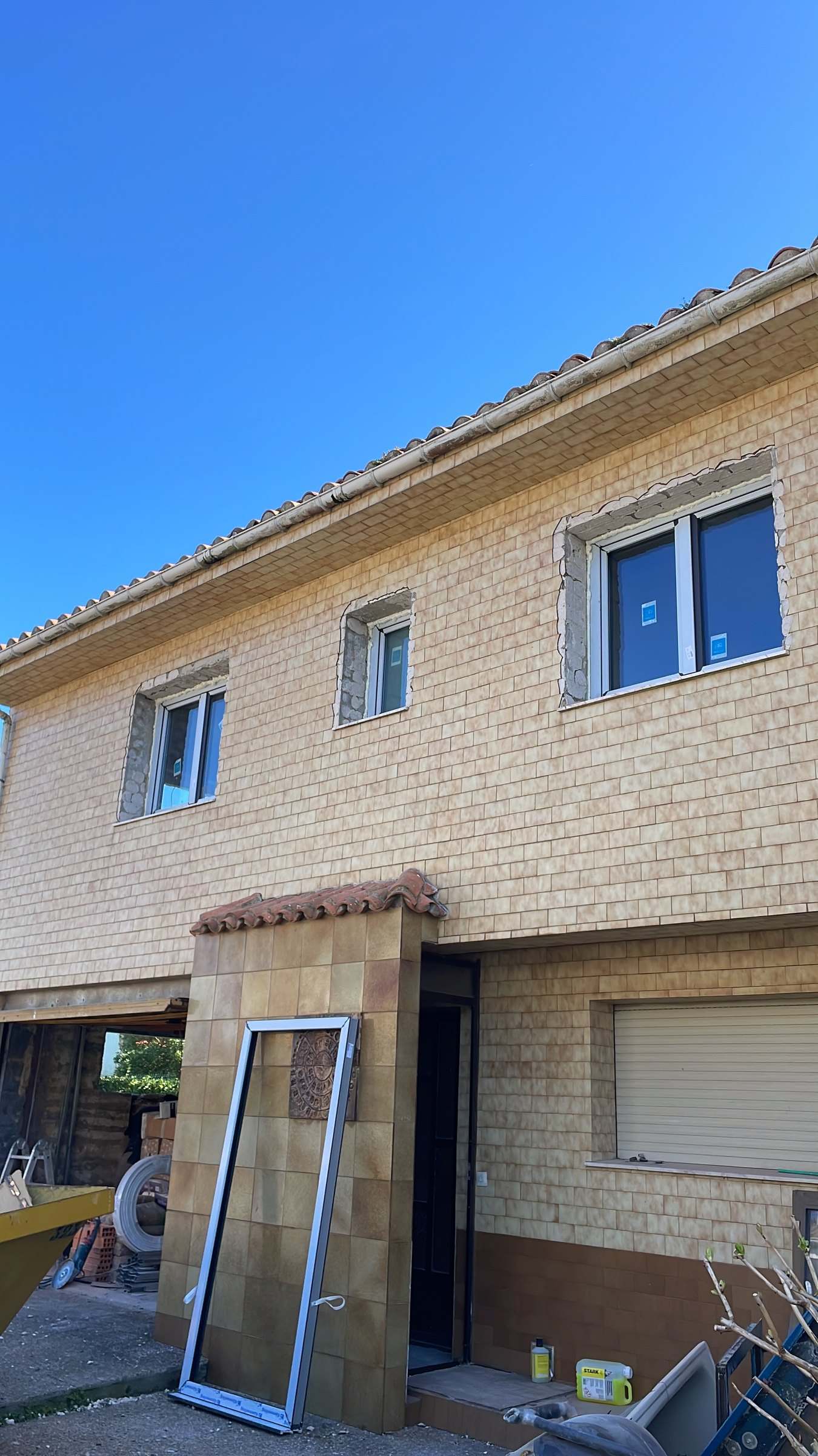 Fachada de plaqueta beige con las ventanas nuevas recién colocadas y los huecos todavía sin rematar