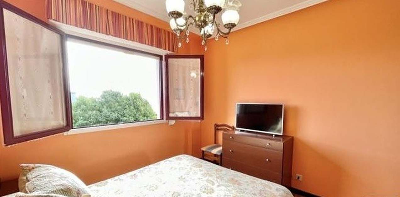 Dormitorio antes de la reforma con paredes naranjas, lámpara de brazos y cómoda de madera
