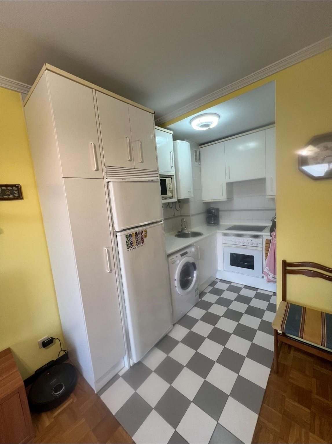 Cocina antigua con muebles blancos y suelo de baldosa ajedrezada