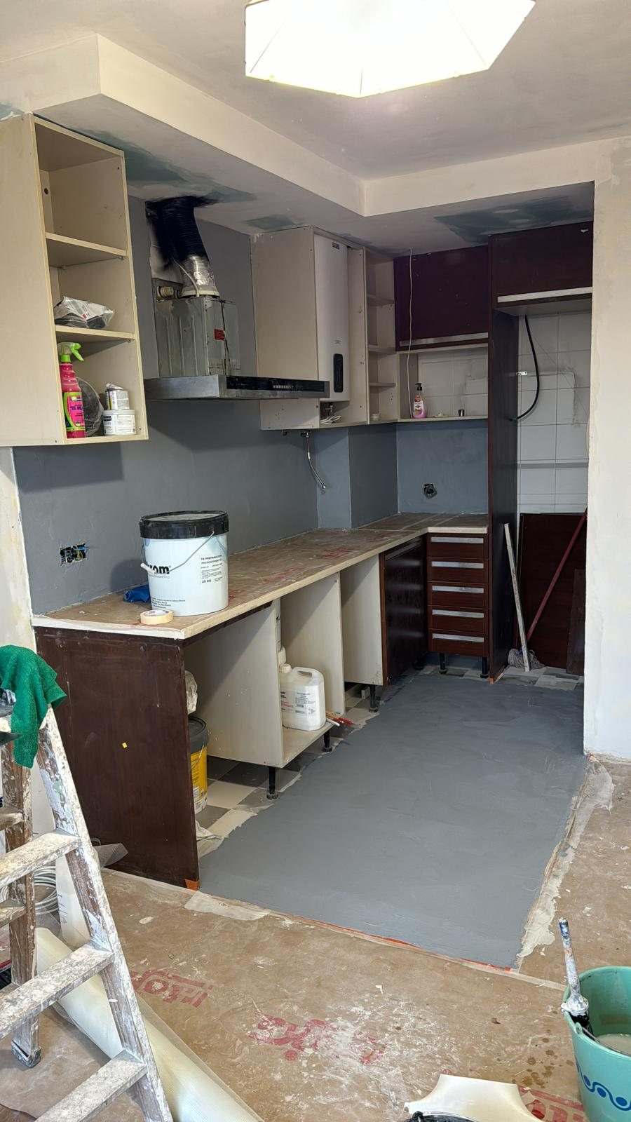 Zona de cocina sin muebles, con el suelo recrecido en gris y el techo nuevo con foseado