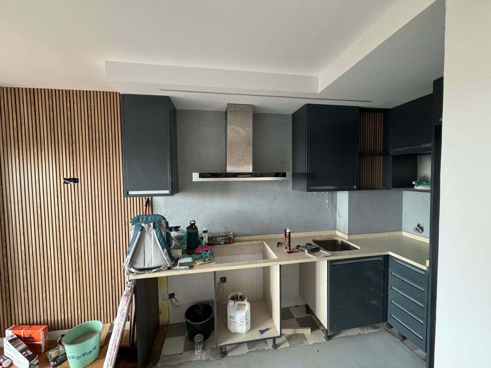 Cocina en L antracita montada, con la campana colocada y la encimera todavía sin terminar