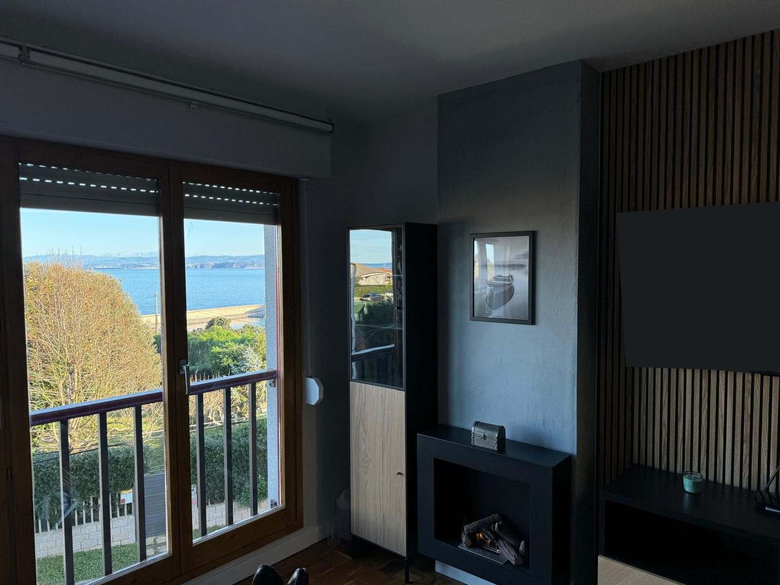 Salón terminado con ventanal y vistas a la bahía, paredes grises y panel de listones