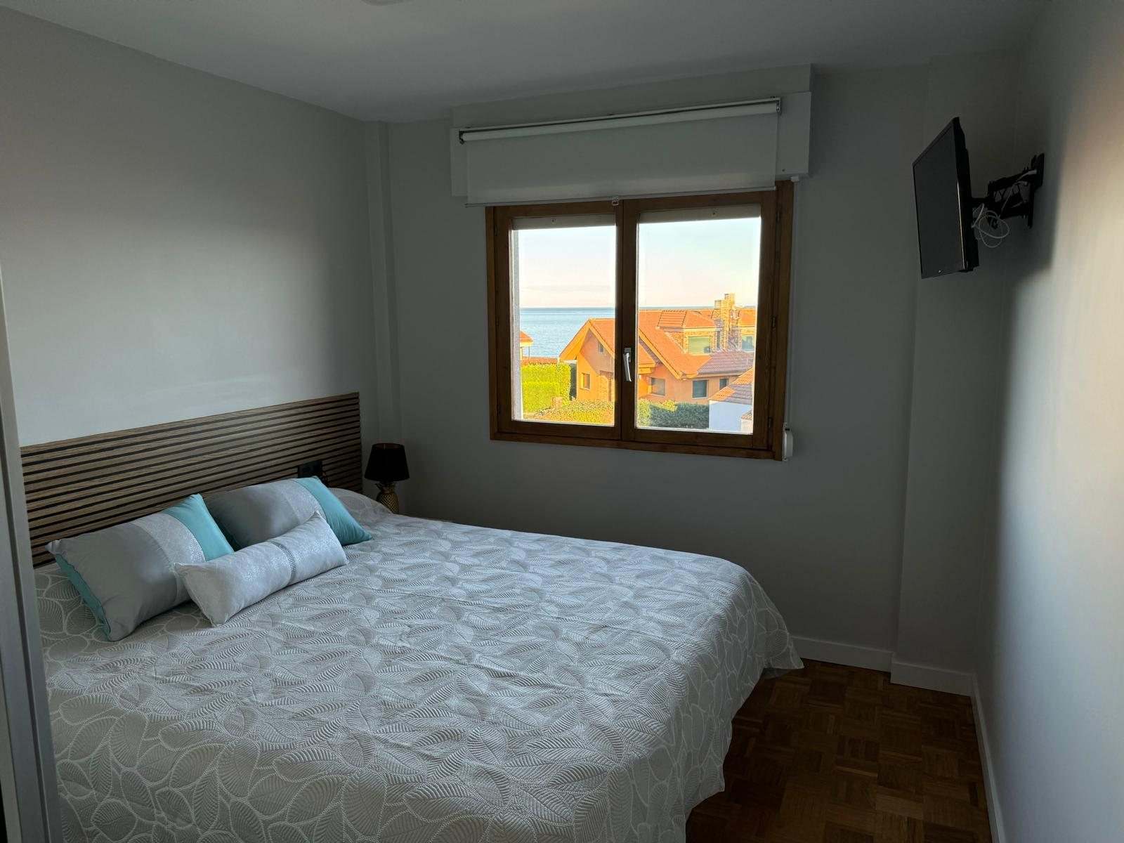 Dormitorio principal gris con cabecero de listones de madera y ventana con vistas