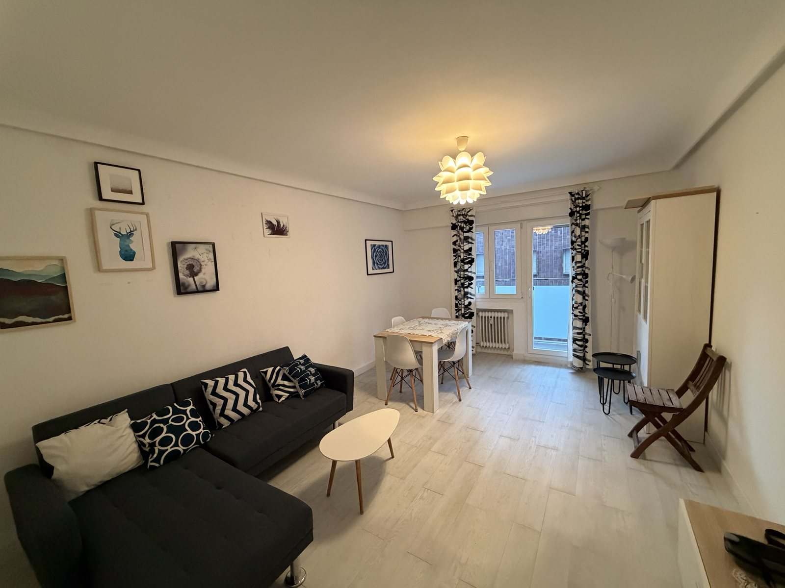 Salón con sofá, mesa de comedor y puertas al balcón