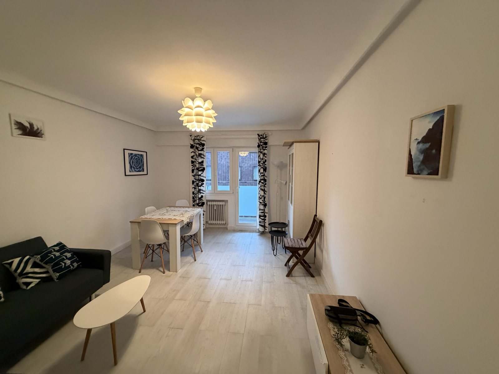 Zona de comedor del salón junto al balcón, con radiador y muebles blancos