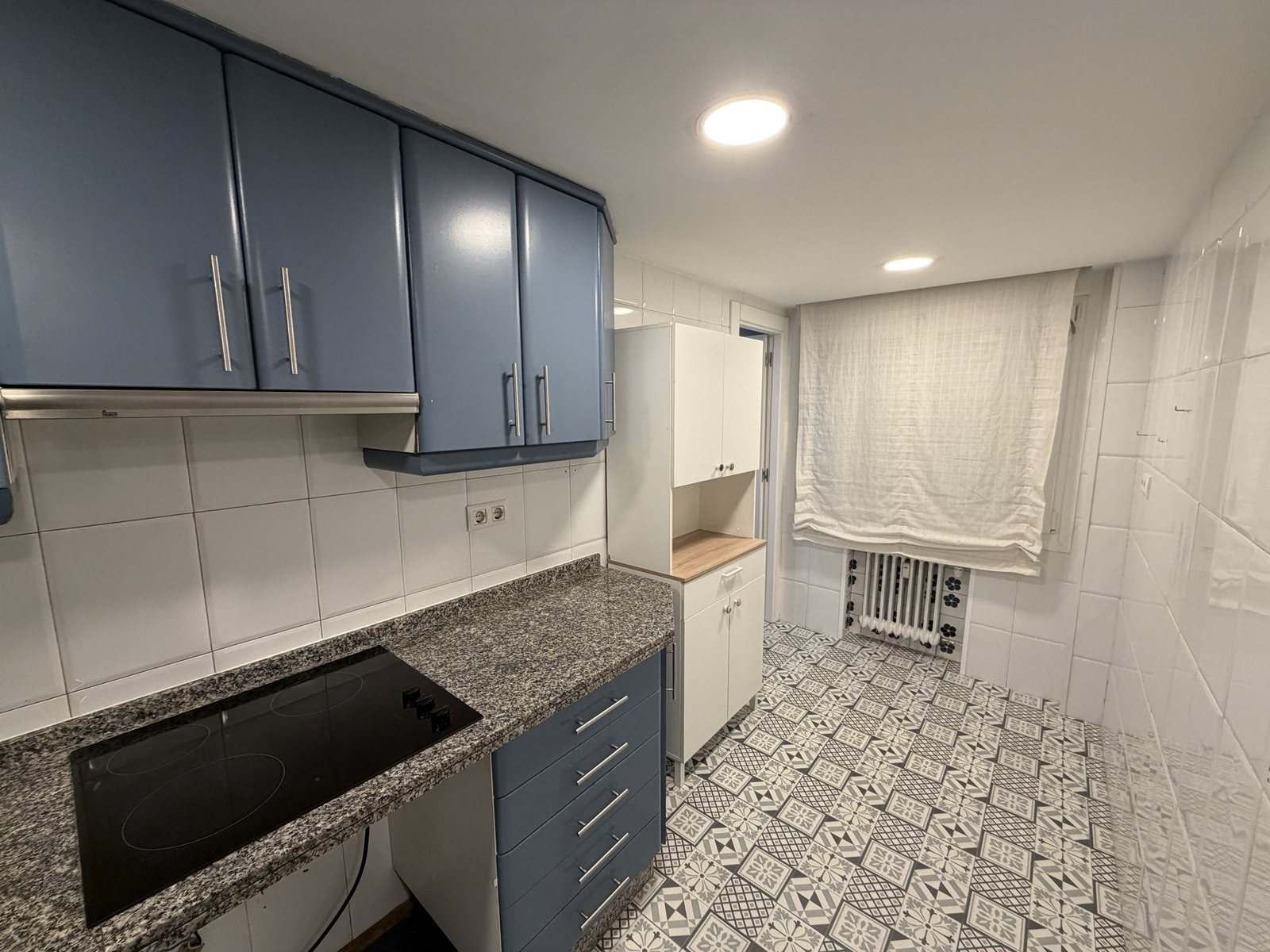 Cocina con muebles azules, encimera de granito y suelo hidráulico