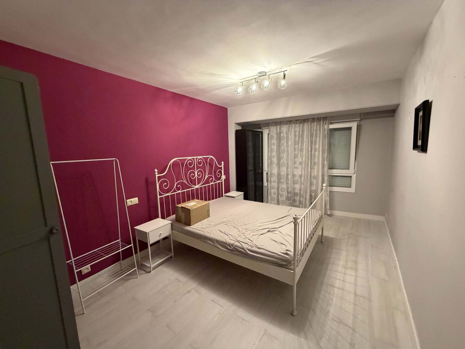 Dormitorio principal con pared fucsia, cama de forja blanca y ventana