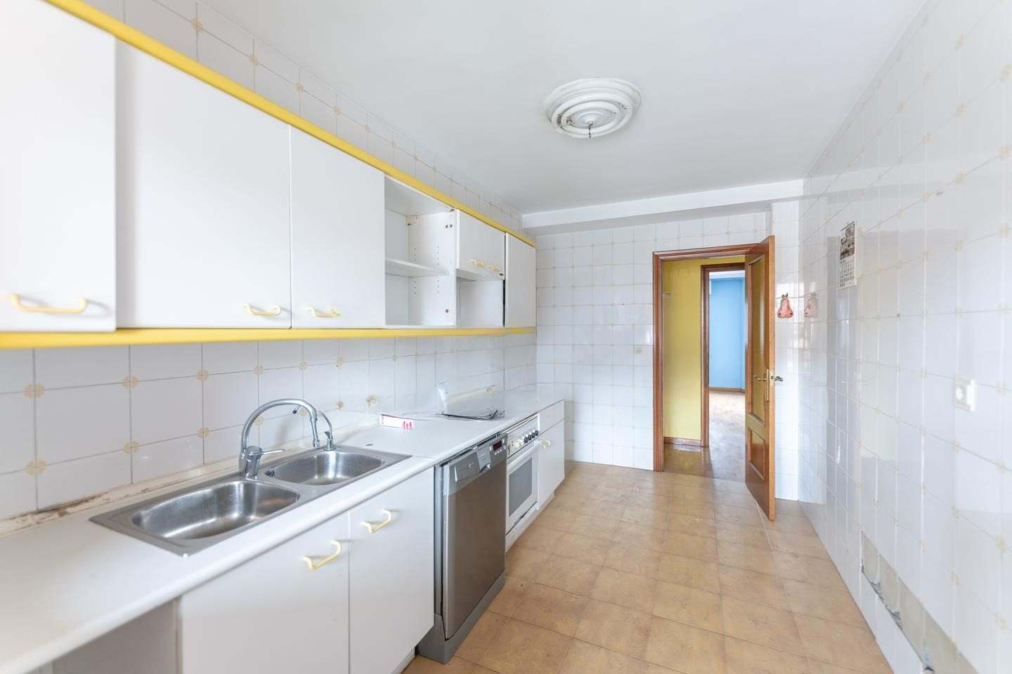 Cocina con fregadero doble, encimera blanca y puerta al pasillo