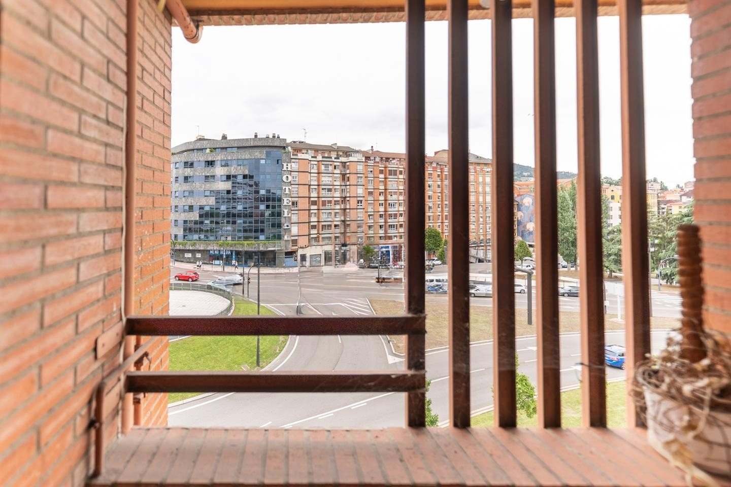 Terraza-tendedero cerrada con lamas de madera y vistas a la avenida