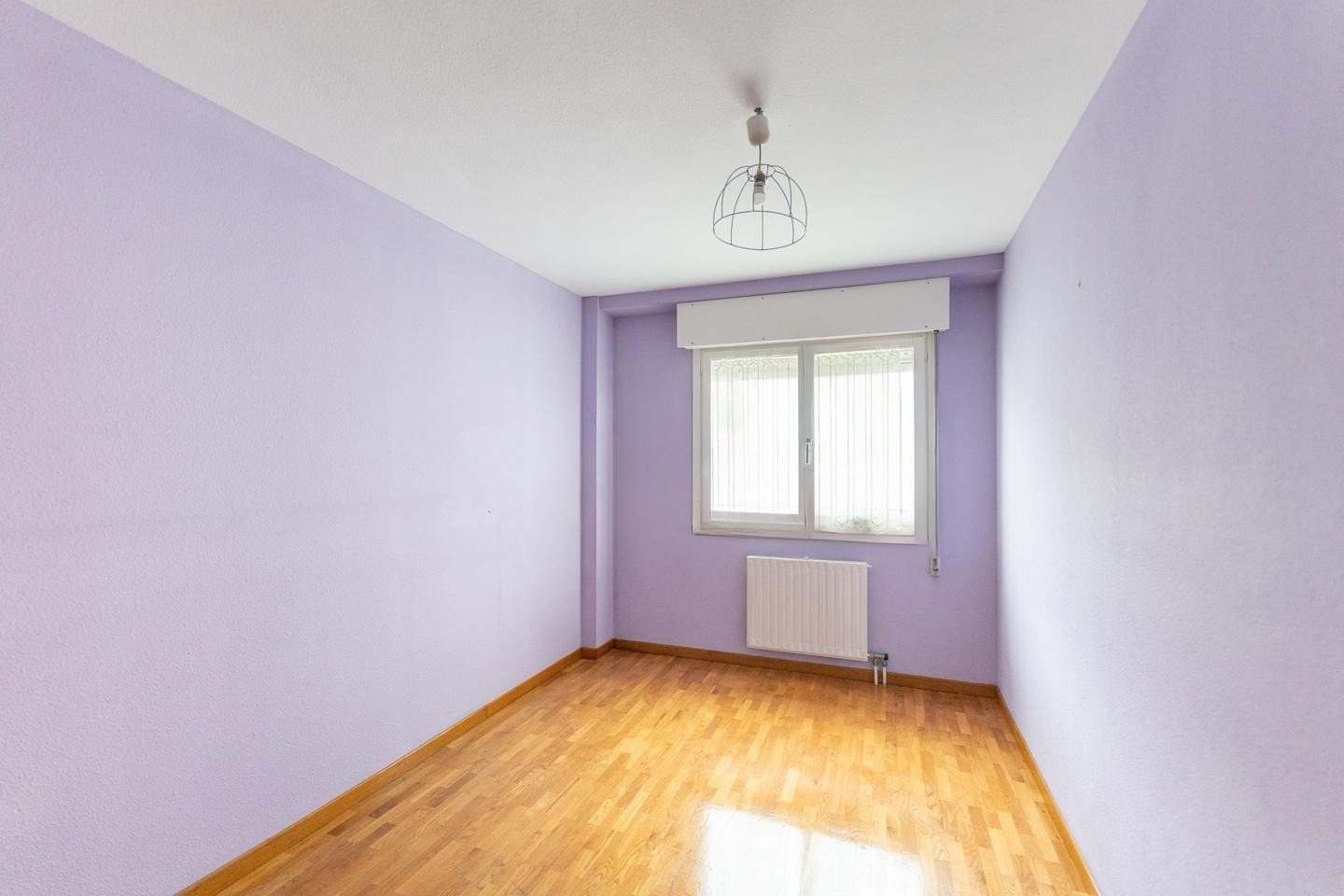 Dormitorio con paredes lilas, suelo de parquet y ventana
