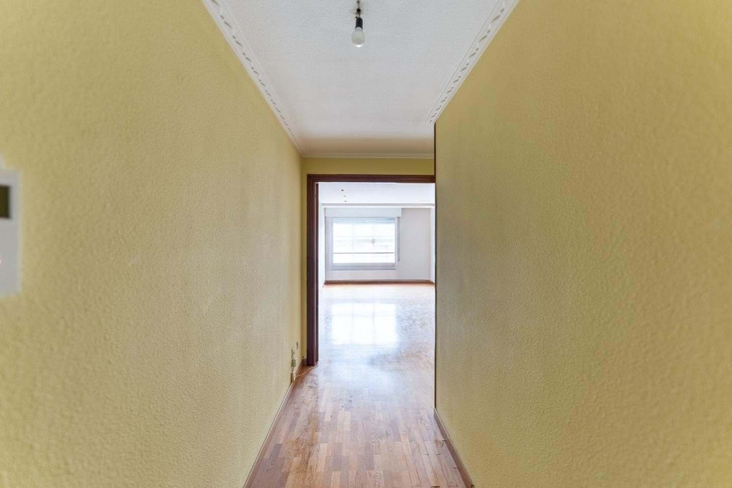 Pasillo largo con suelo de parquet y paredes amarillas